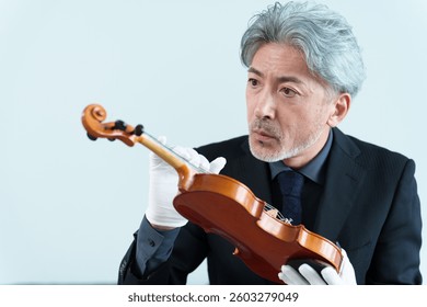 middle aged asian man inspecting violin