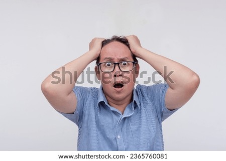 A middle aged asian man pulling his hair in worry. Extremely stressed out. Isolated on a white backdrop.