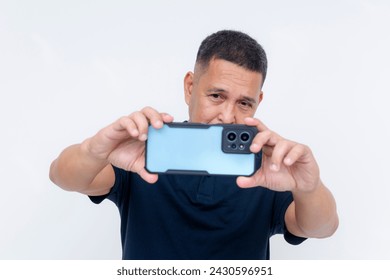 A middle aged asian man taking a landscape mode photo with his high-end smartphone. Advertisement of phone camera features and lens. Isolated on a white background.