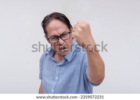 A middle aged asian man threatens to hit someone with his fist if they come closer. A hotheaded dad with confrontational behavior. Isolated on a white backdrop. Stock photo © 