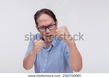 A middle aged asian man threatens to hit someone with his fist if they come closer. A hotheaded dad putting his guard stance up. Isolated on a white backdrop. Stock photo © 