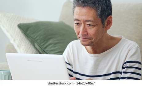 Middle Aged Asian Man Using A Laptop Computer.