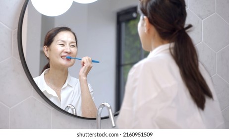 Middle Aged Asian Woman Brushing Teeth