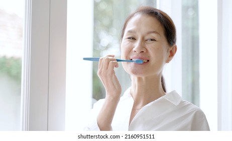 Middle Aged Asian Woman Brushing Teeth