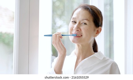 Middle Aged Asian Woman Brushing Teeth