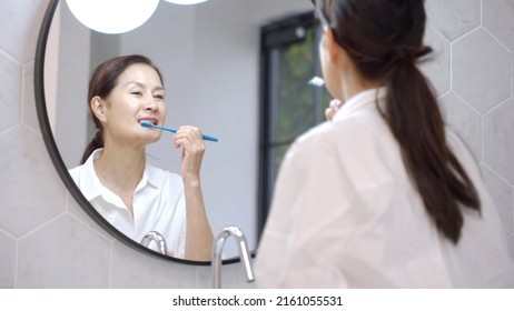 Middle Aged Asian Woman Brushing Teeth