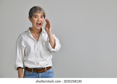 Middle Aged Asian Woman Is Holding Hand Near Mouth And Telling A Secret Isolated On White Background