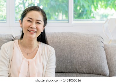 Middle Aged Asian Woman Portrait Sitting On A Couch Indoors.