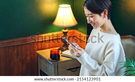 Middle aged Asian woman using a smart phone in the room.