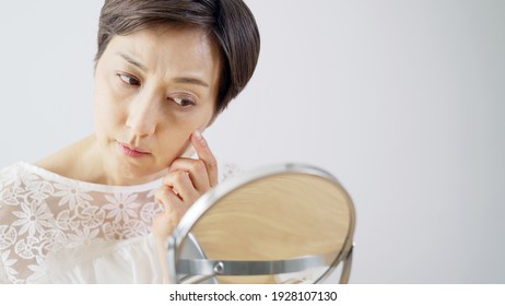 Middle aged Asian woman worrying about her facial skin. Rough skin. Beauty concept. Skin care. - Shutterstock ID 1928107130