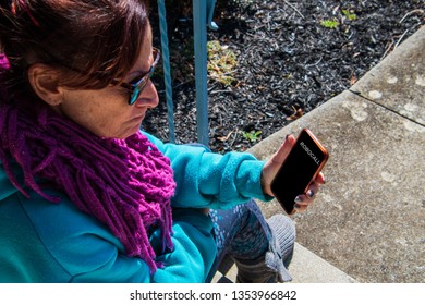 Middle Aged Baby Boomer Caucasian Woman Looking At Her Phone With Anger. The Cell Phone Screen Says Robocall