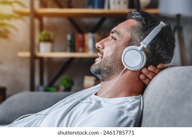 Middle aged bearded man listening music with headphones relaxed in sofa at his home copy space, closeup. Time to relax. Happy person guy in headset with eyes closed relaxing on couch in living room - Powered by Shutterstock