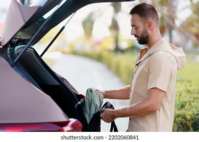 Middle Aged Bearded Man Loading Bag In Car Trunk, Transportation Concept