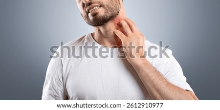 Middle aged bearded man scratching highlighted with red neck on grey studio background, copy space. Annoyed man suffering from itch, having rash on his neck. Allergic reaction, eczema concept