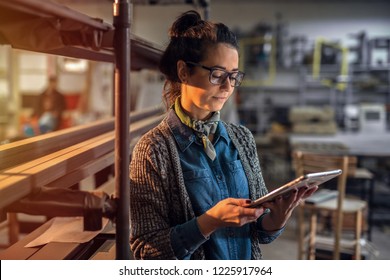 Middle Aged Beautiful Woman Standing In Her Work Shop At Looking At The Tablet.