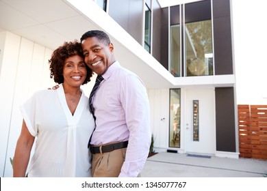 Middle Aged Black Couple Stand Outside Looking To Camera In Front Of Their Modern Home, Close Up