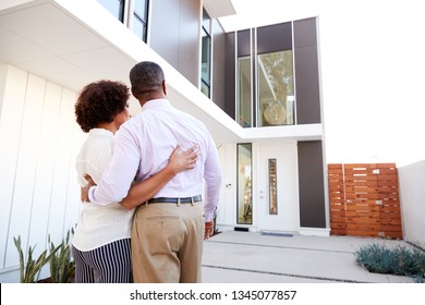 Middle Aged Black Couple Stand Outside Admiring Their Modern Home, Back View