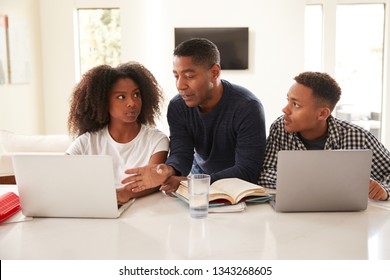 Middle aged black dad helping his teen kids with their homework, front view, close up