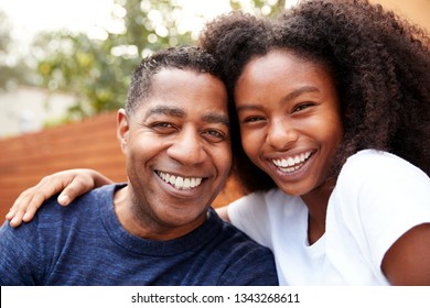 Middle Aged Black Dad And Teenage Daughter Embracing And Smiling To Camera, Close Up