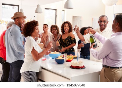 Middle Aged Black Man Opening Champagne To Celebrate At Home With His Three Generation Family