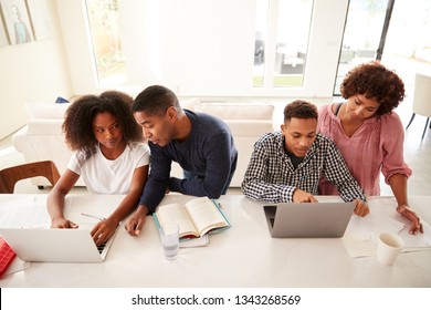 Middle aged black parents helping their teenage kids using laptops to do homework, elevated view