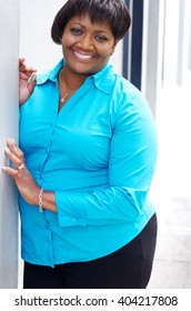 A Middle Aged Black/african American Woman Smiling And Happily Leaning Against A Wall