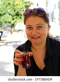 Middle Aged Blonde Woman Holds Traditional Turkish Teacup. Thin Belly, Tea Cup Traditional Serving Style In Turkey For Hot Black Tea.