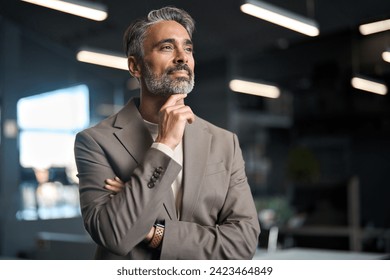 Middle aged business man investor, doubtful mature male ceo executive wearing suit standing in office holding hand in chin looking away at work thinking on leadership question, feeling doubt. - Powered by Shutterstock