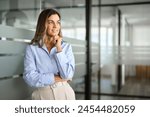 Middle aged business woman investor entrepreneur standing in office looking away. Mature professional businesswoman corporate leader ceo manager at work thinking of future success. Copy space.