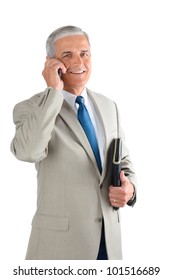 Middle Aged Businessman Talking On His Cell Phone And Carrying A Binder. Man Is Smiling And Looking At Camera Over A White Background.