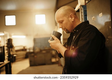 Middle aged car mechanic taking a coffee break while working in a mechanics shop - Powered by Shutterstock