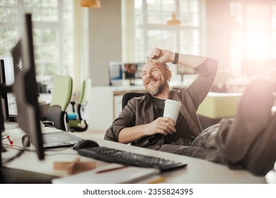 Middle aged caucasian man drinking coffee at a computer desk job - Powered by Shutterstock