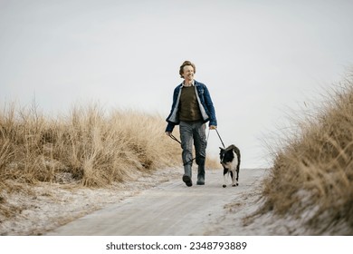 Middle aged caucasian man walking his border collie dog on a winter beach - Powered by Shutterstock