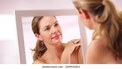 Middle Aged Caucasian Woman Looking At Reflection In Mirror In The Morning