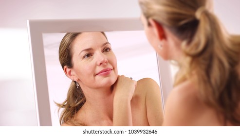 Middle Aged Caucasian Woman Looking At Reflection In Mirror In The Morning