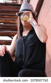 A Middle Aged Caucasian Woman Is Sitting Down Taking A Drink From A Glass.