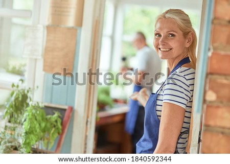 Middle aged caucasian woman welcoming into garden house