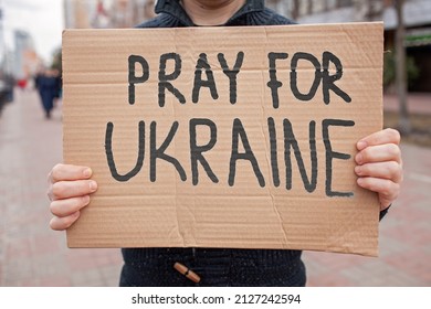 Middle aged civil man stands on crowded city street and holds a poster with anti-war message. Protest against the Russian intervention to Ukraine, activism and human rights movement - Shutterstock ID 2127242594