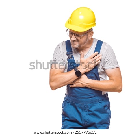 Middle aged construction worker having heart attack, craftsman has pain and holds hands on chest, isolated on white background. Craftsman against white wall