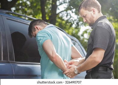 Middle aged cop putting handcuffs on drunk driver