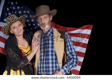 Middle aged country and western couple with traditional outfit in front of american flag. Pride smile on face. Dark background