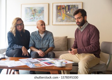 Middle Aged Couple Consulting Interior Designer About Renovation Project. Men And Woman Sitting In Living Room At Home And Talking. Home Decoration Work Concept