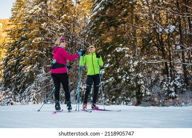 Middle aged couple, cross country skiers, standing on a ski trail and looking at incredible snow mountain peaks. A man pointing at the mountain range.