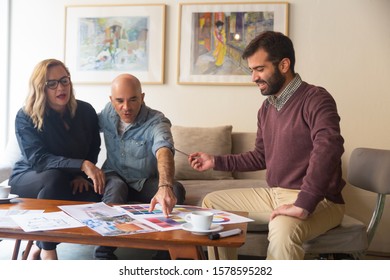 Middle Aged Couple Discussing Renovation Project With Designer And Choosing New Wall Colors. Men And Woman Sitting In Living Room At Home And Talking. Interior Design Concept