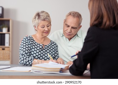 Middle Aged Couple Discussing Something on the Document to a Female Agent at the Table.