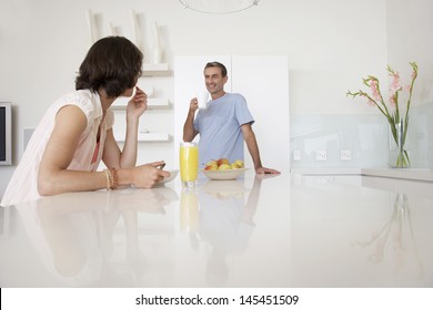 Middle aged couple having breakfast at kitchen bench - Powered by Shutterstock