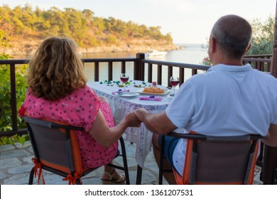 Middle aged couple holding hands having a romantic dinner date on terrace with sea view at sunset. Valentines day and holiday concept. - Powered by Shutterstock