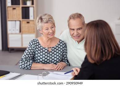 Middle Aged Couple Listening to a Female Agent Discussing Some Business to them at the Table.