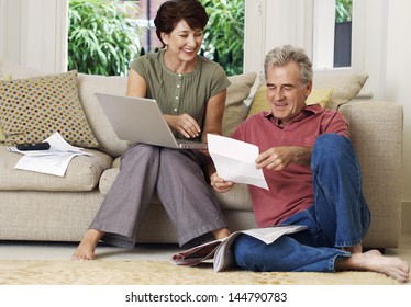 Middle Aged Couple Looking At Bill And Laptop In The Living Room