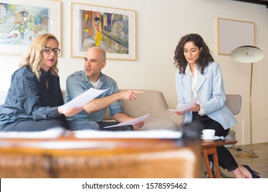 Middle Aged Couple Meeting With Notary And Reading Documents. Man And Women Sitting In Living Room At Home And Talking. Legal Expert Consulting Concept